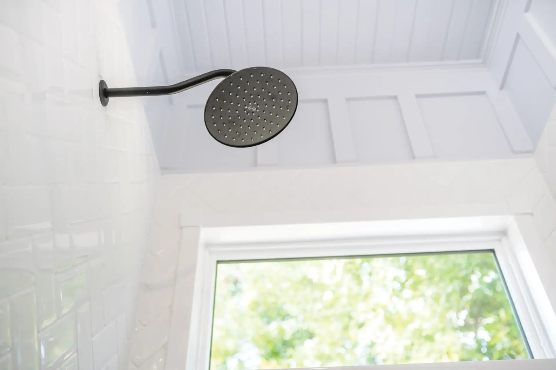 White shower with shower head and window in background
